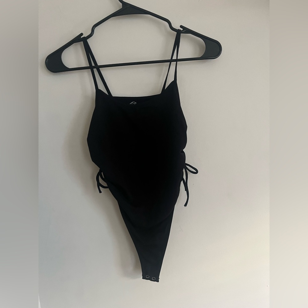Black “Suzette” body suit with ribbed detail on each side with tie